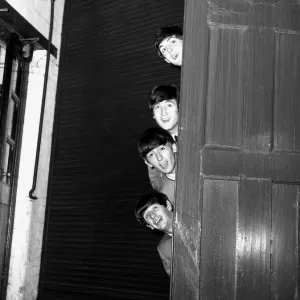 I Beatles che sbirciano fuori da dietro una porta prima dell'apparizione del gruppo nella serata della domenica.