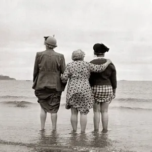 Tres mujeres miran al mar observando un barco desaparecer en el horizonte agarrándose a las faldas.