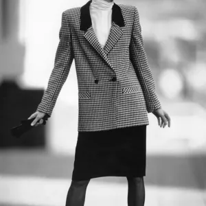La moda femenina de la década de 1980: Nuestra modelo lleva un chaqueta con solapas doblemente forradas con cuadros y un vestido negro. La moda femenina de la década de 1980: Nuestra modelo lleva un chaqueta con solapas doblemente forradas con cuadros y un vestido negro.