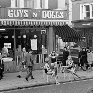 Models wearing swimsuits sit outside Guys and Dolls in the Kings Road Chelsea London
