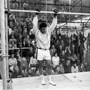 Muhammad Ali in a cage protected by glass from hundreds of fans who paid 50p to watch him