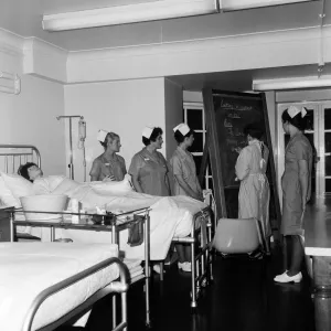 Nurses receiving instruction from Miss V Thomas (in surgical gown) on patient care