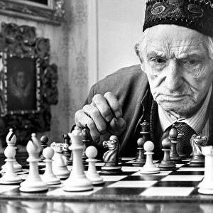 An old gentleman studying a chess board