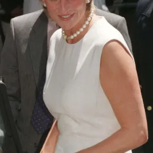 Princess Diana, wearing a white dress and necklace during a visit to a rehabilitation