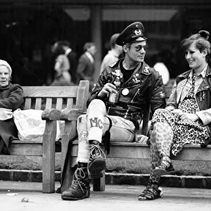 Two punk rockers sitting on a bench in Birmingham, seated next to them is an elderly lady