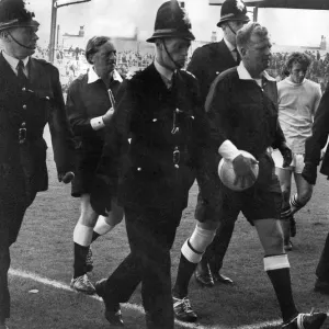 Referee David Smith gets a police escort as he leaves the Maine-road pitch following a