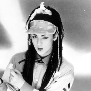 Singer Boy George with hair extensions wearing a cap with his name on it