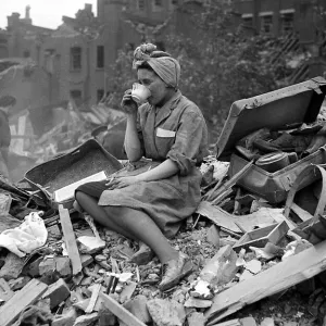 A woman enjoys a cup of tea in the midst of the bomb damage at New Cross after air raids