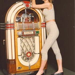 A woman poses next to a Wurlitzer juke box
