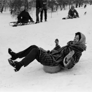 A woman sledging on a washing up bowl in Greenwich Park, London, 27th December 1970