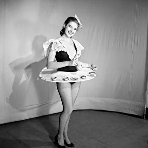 Woman wearing a skirt that is also a tray, seen here with tea pot and cups on the tray