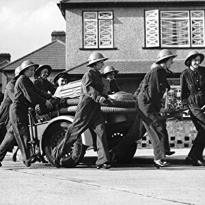 Women fire fighters from Erith Kent walk beside their trailer pump during WW2 1942