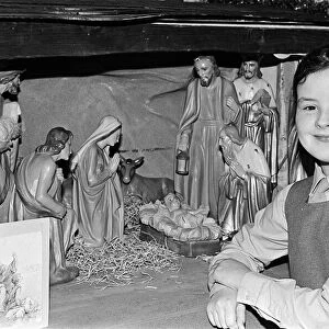 A young girl standing next to a Christmas Nativity scene. Teesside, December 1985
