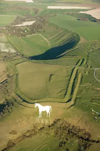 Prints of BRATTON CAMP AND WHITE HORSE, Westbury, Wiltshire. Aerial view. Below an Iron Age hill fort, enclosing a much earlier long barrow, stands the Westbury White Horse Monuments And Memorial Prints: Bratton Camp and White Horse Print
