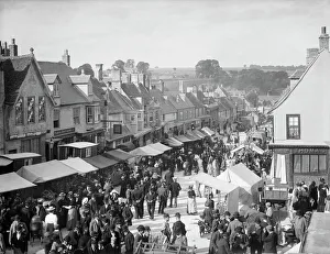 <b class=qtipBold><figcaption>Burford Mop Fair CC57_00428</figcaption></b><br>BURFORD, Oxfordshire. A view of the High Street during the Hiring Fair (Mop Fair) with stalls set out. Photographed in 1895 by Henry Taunt.<br><em>© Historic England</em> Burford Mop Fair CC57_00428