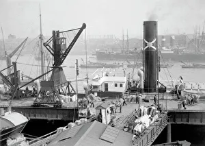 <b class=qtipBold><figcaption>Butler's Wharf BB87_09741</figcaption></b><br>BUTLER'S WHARF, Shad Thames, London. Crates of goods wrapped in straw for protection are unloaded in London and set on the conveyor belt to the warehouses. The small hut in the centre of the picture is probably where the overseer kept records of the cargo. From the Butlers Wharf Collection: some time before 1910 the Directors of Butlers Wharf Ltd, commissioned a series of photographs detailing aspects of the company's work.<br><em>© Historic England</em> Butler's Wharf BB87_09741