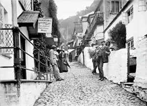<b class=qtipBold><figcaption>Clovelly BB73_07823</figcaption></b><br>High Street, Clovelly, Devon. Looking up the cobbled main street in Clovelly, showing the New Inn on the north side of the street, with people leaning against the walls of the buildings. In 1914 the New Inn was rebuilt on the south side of the street. Photographed 1880-1914.<br><em>© Historic England Archive</em> Clovelly BB73_07823