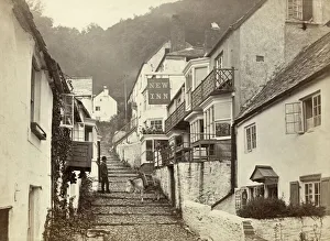 <b class=qtipBold><figcaption>Clovelly, Devon OP04926</figcaption></b><br>CLOVELLY, Torridge, Devon. A view up the main cobbled street in Clovelly, with a donkey on the cobbles and a woman standing on the terrace of the New Inn talking to a man below. Donkeys are still used to transport goods up the steep cobbled street in Clovelly. Photographed by Francis Bedford. Date range: 1850-1900.<br><em>© Historic England</em> Clovelly, Devon OP04926