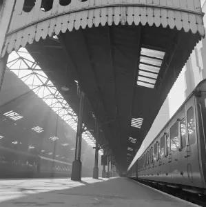 Prints of MARYLEBONE STATION, London. View along a deserted platform at Marylebone railway station with a train waiting at the platform edge and the canopy valance in the foreground. John Gay Transport Prints: Marylebone Station Print, a1960s photograph of a deserted platform