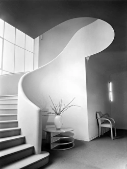 <b class=qtipBold><figcaption>Land's End House CC012271</figcaption></b><br>Staircase at Land's End House, Beggars Hill Road, Charvil, Berkshire, 5 March 1935. Millar & Harris cellulose nitrate negative. The photographers make superlative use of light and shade to create an expressionistic view of the staircase at Land's End House. The house was built in 1935 and designed by architect Guy Morgan for the aircraft manufacturer Frederick George Miles. A full-height window at the front of the house lit this curved rubber-clad staircase. Millar & Harris had been established in 1912 as Millar & Stone, and became Millar & Harris in 1924. The firm's extensive client base included architects such as Guy Morgan, estate agents Knight Frank & Rutley, and the construction company Mowlem.<br><em>© Historic England</em> Land's End House CC012271