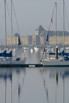 <b class=qtipBold><figcaption>Portchester Castle N071248</figcaption></b><br>PORTCHESTER CASTLE, Hampshire. Viewed from across the estuary showing the church tower and roof above the curtain walls.<br><em>© Historic England</em> Portchester Castle N071248