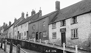 <b class=qtipBold><figcaption>Sherborne in 1939 BB056815</figcaption></b><br>Greenhill, Sherborne, Dorset. Houses on the south side of Greenhill, including Trinity Lodge, Crown Cottage, and numbers 6-11. A lady is looking suspiciously at the photographer from an upstairs window! Photographed in May 1939.<br><em>© Historic England Archive</em> Sherborne in 1939 BB056815