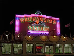 Prints of Walthamstow Stadium, Chingford Road, Walthamstow, Waltham Forest, Greater London. The illuminated neon sign on central parapet of Walthamstow Stadium, seen at night. The sign was erected in 1951 Monuments And Landmark Prints: Walthamstow Stadium Print: Illuminated Neon Sign at Night