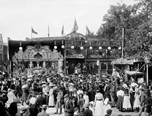 <b class=qtipBold><figcaption>St Giles Fair, Oxford CC49_00539</figcaption></b><br>St Gilesa Fair, Oxford, Oxfordshire, September 1905. Photographed by Henry William Taunt (1842-1922) on silver gelatin glass plate negative. Despite the bustle of St Giles's Fair, the photographer Henry Taunt has inevitably attracted attention perched, presumably on a stepladder, above the fairgoers. Employees of the ornately decorated Taylor's Royal Electric Coliseum are drumming up business, and a Fried Fish and Chip Potato wagon stands beside the gas lamp. St Giles's Fair had evolved from a parish wake first mentioned in 1624 into a major amusement fair with special trains bringing visitors from far afield. Taunt photographed the fair from the late 1860s, hoping of course to sell many images, and also out of personal interest.<br><em>© Historic England</em> St Giles Fair, Oxford CC49_00539
