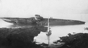 <b class=qtipBold><figcaption>Stranded submarine JXC01_01_011</figcaption></b><br>Falmouth, Cornwall. A view from the shore showing people aboard the wreck of UB 112, on the rocks west of Pendennis Point, with a sailing boat in the foreground. Five German U-boats were moored at Falmouth after being surrended to the Royal Navy in 1918. After several were stranded in 1921 the submarines were broken up in situ. Photographed by Captain Jack Casement in 1921.<br><em>© Historic England Archive</em> Stranded submarine JXC01_01_011
