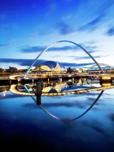 Prints of MILLENNIUM BRIDGE, Newcastle upon Tyne / Gateshead, Tyne and Wear. Floodlit view of the Millennium Bridge at twilight with The Sage and Tyne Bridge beyond Northern Ireland Prints: Millennium Bridge Print - Floodlit Twilight View
