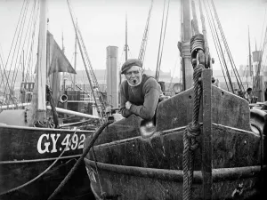 Prints of Grimsby, North East Lincolnshire. A crewmaster aboard one of the fishing boats in Grimsby Harbour. Photographed by Alfred Newton and Sons in July 1899 Alfred Prints: Grimsby Crewmaster Print (1899) - A photograph of a man in a fishing boat