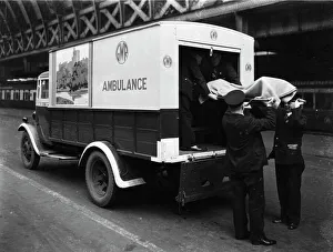 GWR staff loading a stretcher into a parcel van which has been converted into an GWR staff loading a stretcher into a parcel van which has been converted into an