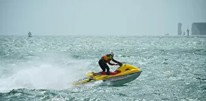 RNLI lifeguard on a rescue watercraft off Sandbanks beach, Poole. Moving from left to right at speed