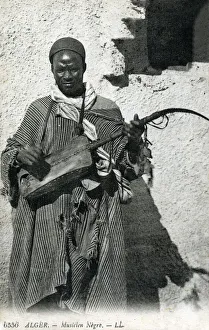 Algeria - African Gnawa Musician playing a traditional sintir, also known as the guembri, gimbri or hejhouj Algeria - African Gnawa Musician playing a traditional sintir, also known as the guembri, gimbri or hejhouj
