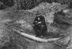 An archaeologist sits next to the unearthed remains of a st An archaeologist sits next to the unearthed remains of a st