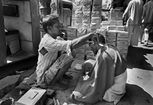 A barber squats in the street in Chandni Chouk, Old Delhi A barber squats in the street in Chandni Chouk, Old Delhi