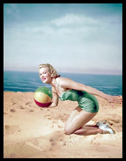<b class=qtipBold><figcaption>Beach Ball Girl / Woof</figcaption></b><br>Pretty blonde bathing beauty, wearing white court shoes & a pale blue, halter-neck one- piece costume, poses on a sandy beach holding a small beach ball.<br><em>© Mary Evans Picture Library</em> Beach Ball Girl / Woof