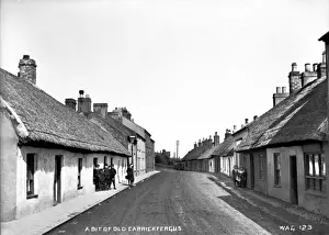Prints of A Bit of Old Carrickfergus - an unusual view with boys and girls on each side of a road with thatched buildings. (Location: Northern Ireland: County Antrim: Carrickfergus). Date: circa early 1900s Carrickfergus Prints: Carrickfergus Thatched Buildings Print circa Early 1900s