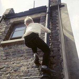 Jeans Gallery: Boy climbing drainpipe on a Balham house, SW London