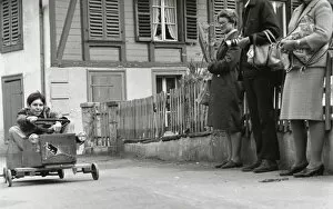Boy on a go-kart passing three adults