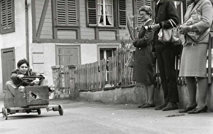 Boy on a go-kart passing three adults Boy on a go-kart passing three adults