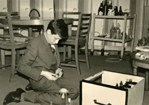 Boy kneeling on the floor sorting out some glass jars Boy kneeling on the floor sorting out some glass jars