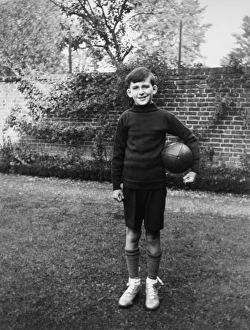 Boy standing in garden with rugby ball, Eltham, London Boy standing in garden with rugby ball, Eltham, London