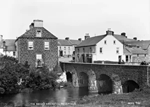 Prints of The Bridge and Hotel, Bushmills - a view of the bridge over the river bush and the hotel. There are men on the bridge. (Location: Northern Ireland: County Antrim: Bushmills). Date: circa early 1900s River Prints: Early 20th-Century Print of Bushmills Bridge and Hotel