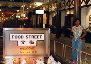 British Caribbean woman stands by Food Street sign, Hong K British Caribbean woman stands by Food Street sign, Hong K