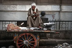 Cairo street seller sits on his barrow smoking a cigarette Cairo street seller sits on his barrow smoking a cigarette