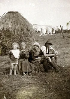 Four children sitting in a farmer's field near a hayrick Four children sitting in a farmer's field near a hayrick
