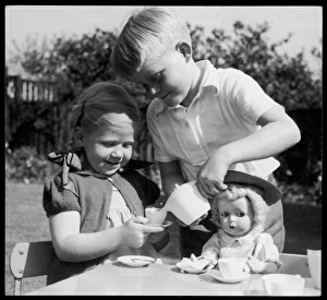 <b class=qtipBold><figcaption>Children's Doll & Teaset</figcaption></b><br>A boy pretends to pour tea for a little girl and her doll<br><em>© Mary Evans Picture Library</em> Children's Doll & Teaset