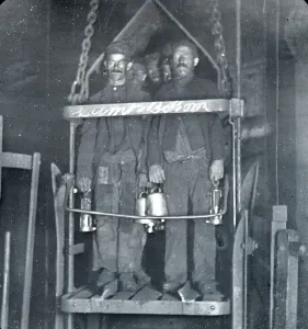 Prints of Several coal miners with blackened faces stand in the shaft lift at the end of their shift in a coal mine in South Wales Wales Prints: Coal Miners in Shaft Lift Print, South Wales