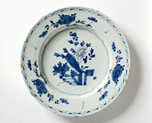 <b class=qtipBold><figcaption>Delftware plate</figcaption></b><br>Tin-glazed earthenware plate painted in blue with a central floral design, three sprays of flowers on the rim, and an outer border of crosses and dashes in two concentric lines, made in the Netherlands c.1760. Date: c.1760<br><em>© The Geffrye Museum of the Home / Mary Evans Picture Library</em> Delftware plate